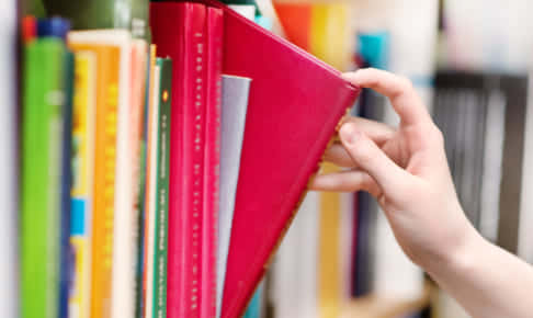 closeup hand selecting book from a bookshelf